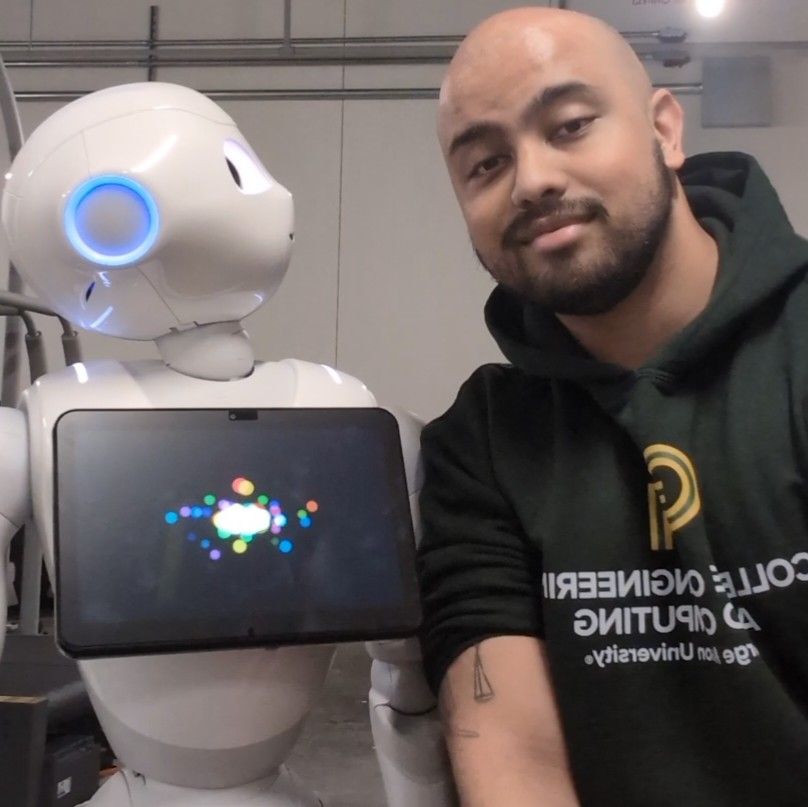 Alex Veerasammy beside a humanoid robot.